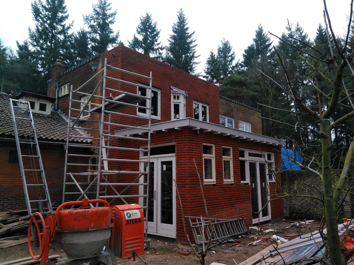 Aanbouw in rode baksteen in aanbouw met steiger en betonmolen