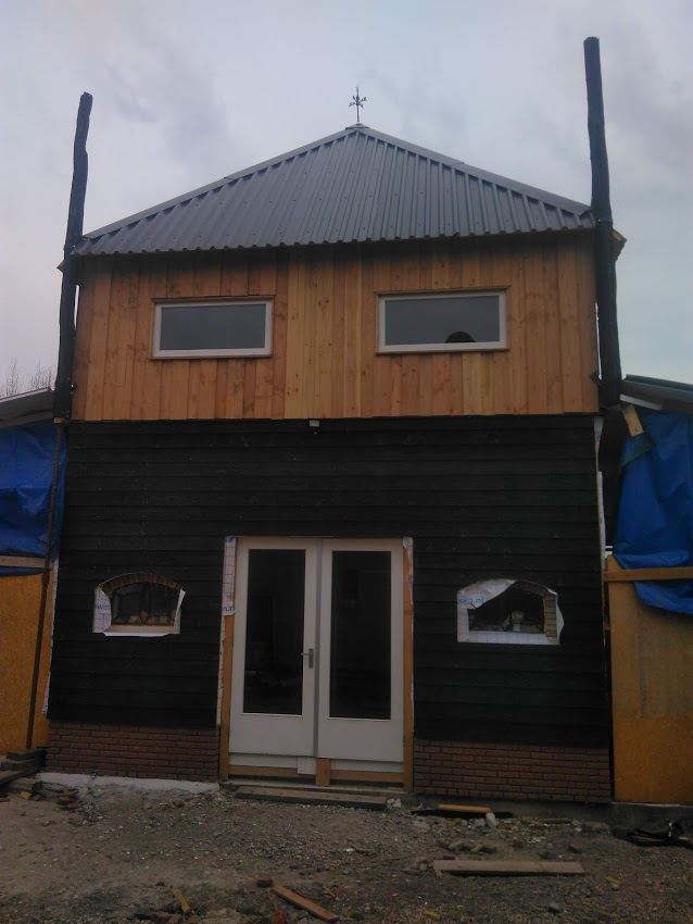 Houten gevel met zwarte potdekseldelen en dubbele deuren
